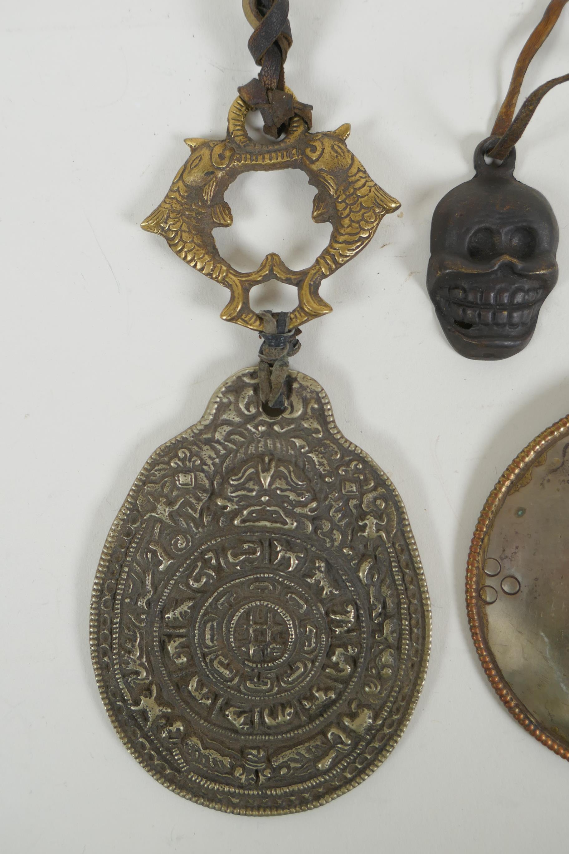 A Tibetan metal calendar, a convex mirror pendant and a cast iron skull pendant, 10cm diameter - Image 2 of 5