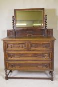 An early C20th oak Jacobean style dressing table, the swing mirror on barley twist columns, two over