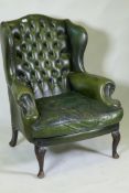 A green leather buttoned wingback armchair