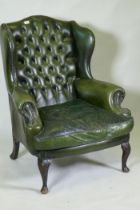 A green leather buttoned wingback armchair