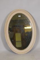 An antique painted wood and composition oval shaped wall mirror, 90 x 60cm