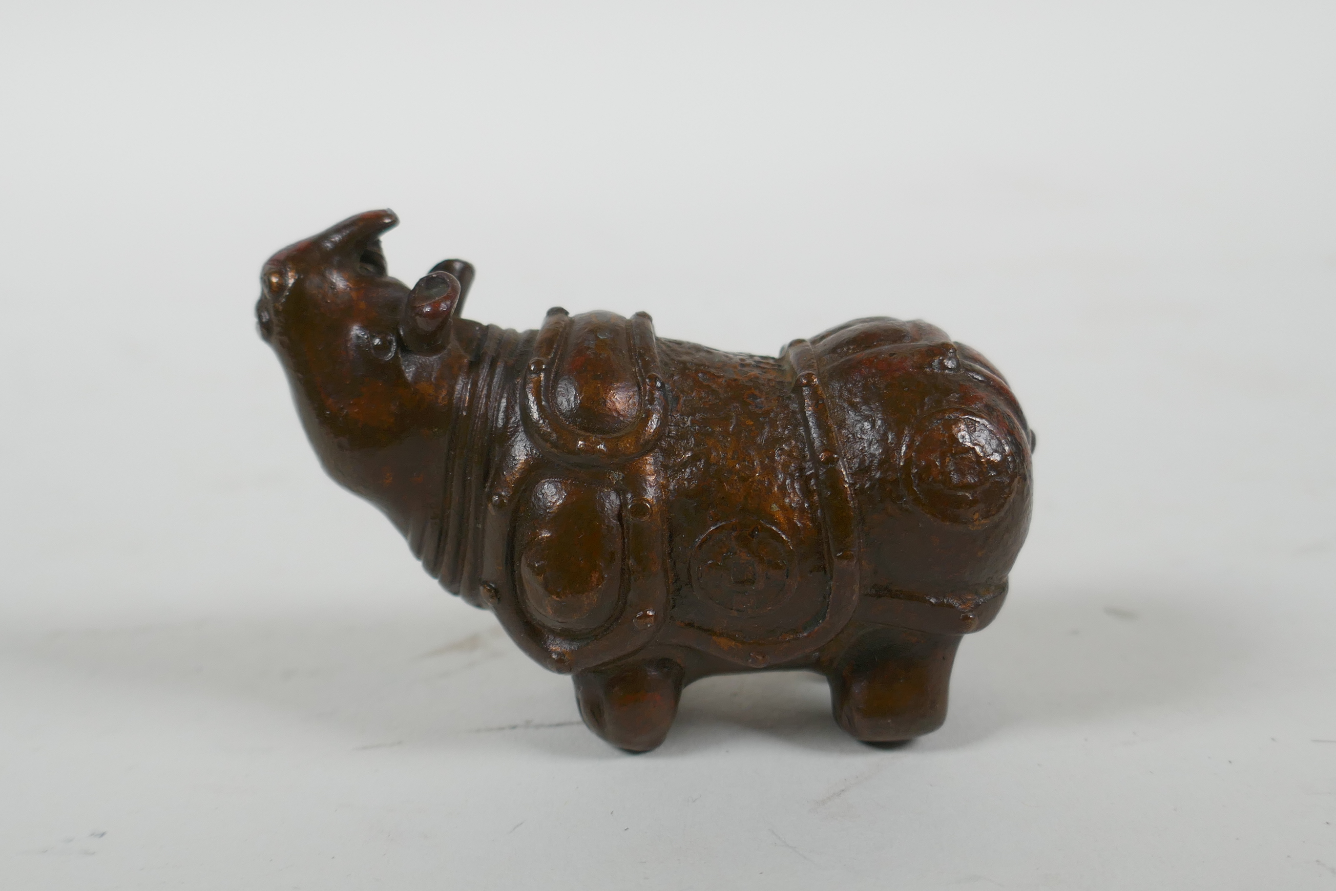 A Japanese style bronze okimono rhinoceros, 6.5cm long