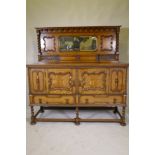 An early C20th oak Jacobean style mirror back sideboard, with two cupboards opening to reveal