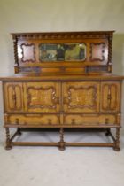An early C20th oak Jacobean style mirror back sideboard, with two cupboards opening to reveal
