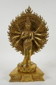 A Tibetan gilt bronze figure of a many armed deity standing on a lotus flower, 32cm high