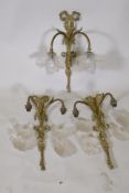 A set of three brass two branch wall lights with individual etched glass petal shaped shades,