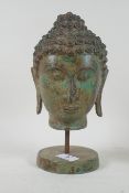 A vintage bronze Buddha's head with green patination, mounted on a stand, 27cm