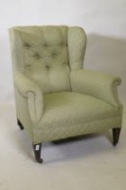 A Victorian wing back arm chair, raised on square tapering supports with brass castors