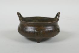 A Chinese bronze censer with two handles, character decoration and tripod supports, impress Xuande 6