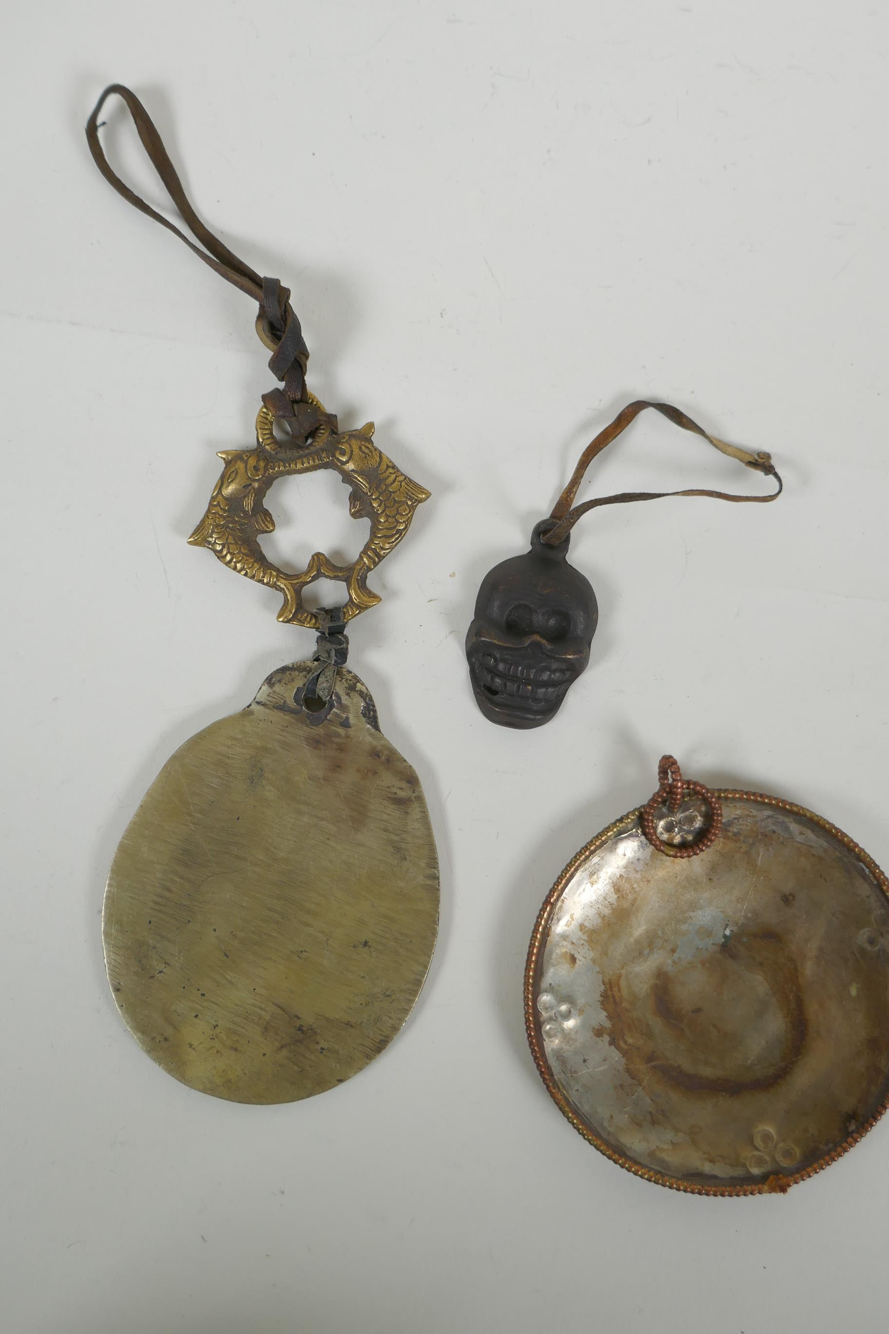 A Tibetan metal calendar, a convex mirror pendant and a cast iron skull pendant, 10cm diameter - Image 5 of 5