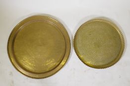 An Islamic brass tray with script decoration, together with another larger decorated with Islamic