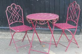 A painted iron bistro set of two folding chairs and a table, 62cm diameter
