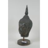 A bronze Buddha's head mounted on a metal stand, 32cm high