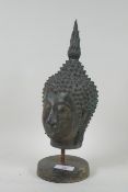 A bronze Buddha's head mounted on a metal stand, 32cm high