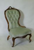 A Victorian carved walnut nursing chair, raised on cabriole supports with brass castors