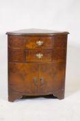 A bow fronted walnut corner cabinet, with two drawers over two cupboards, raised on bracket