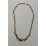 An antique graduated amber swirled glass necklace, 78cm long