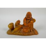 A Chinese imitation amber soapstone carving of Lohan, the base carved for seal, 16cm long