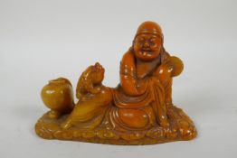 A Chinese imitation amber soapstone carving of Lohan, the base carved for seal, 16cm long