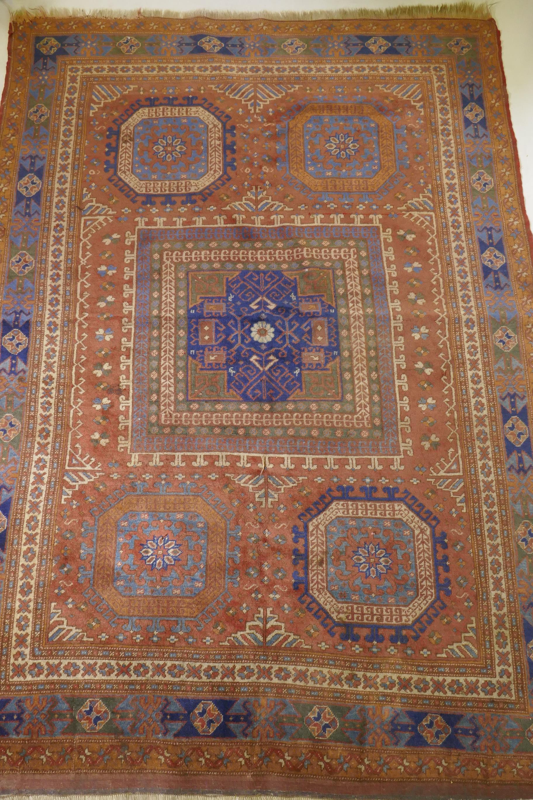 An antique Bergama carpet, with geometric designs on a terracotta coloured field and soft sheen to