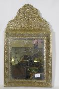 A C19th French brass cushion mirror, with grape and vine decoration, floral crest and inset bevelled