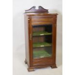 An Edwardian music cabinet with shaped lift up top, single glazed door and labelled shelves and