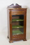 An Edwardian music cabinet with shaped lift up top, single glazed door and labelled shelves and