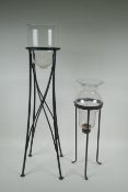 A glass hurricane vase on a wrought iron stand, and another, largest 76cm high