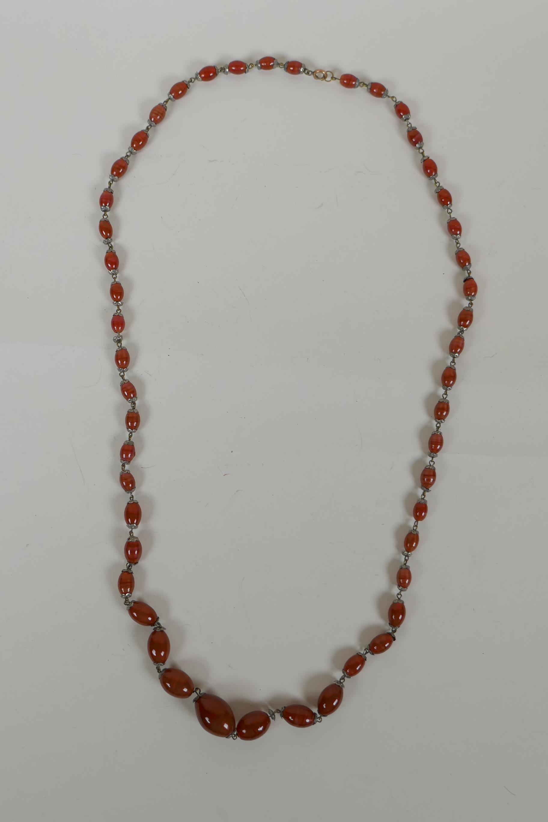 An antique graduated amber swirled glass necklace, 78cm long