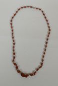 An antique graduated amber swirled glass necklace, 78cm long