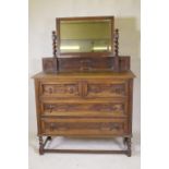 An early C20th oak Jacobean style dressing table, the swing mirror on barley twist columns, two over