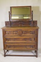 An early C20th oak Jacobean style dressing table, the swing mirror on barley twist columns, two over