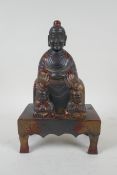 A Chinese cast metal figure of an emperor seated on a throne, with the remnants of gilt patina,