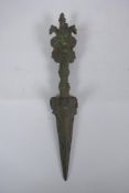 A Tibetan cast iron ceremonial phurba with wrathful deity mask decoration to handle, 32cm long