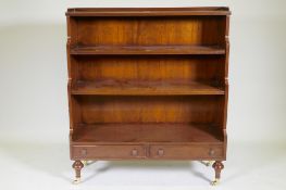 A Regency style mahogany waterfall bookcase with two drawers, raised on turned supports, 96 x 34 x