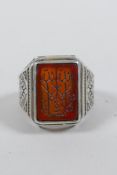 An Islamic white metal ring set with an amber agate intaglio seal, size S/T