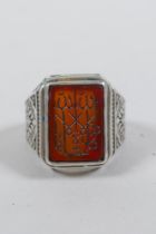 An Islamic white metal ring set with an amber agate intaglio seal, size S/T