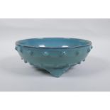 A Chinese celadon glazed porcelain bowl raised on tripod supports, 21cm diameter
