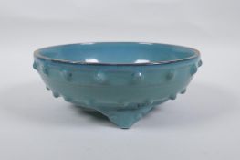 A Chinese celadon glazed porcelain bowl raised on tripod supports, 21cm diameter