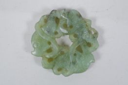 A Chinese carved and pierced mottled green jade pendant with entwined carp decoration, 6cm diameter