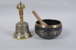 A Tibetan bronze singing bowl with script decoration and wood beater, and a brass ceremonial bell