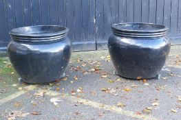 A pair of large black glazed ceramic garden pots, 59cm high, 70cm wide