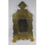 An Islamic brass and hardwood wall mirror with engraved script and scrolling decoration, 33 x 60cm