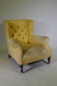 A Victoria deep back wing armchair, raised on on turned supports