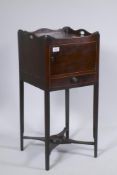 A George III mahogany pot cupboard with a shaped gallery top and single door over a cross stretchers