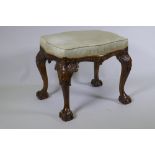A Georgian style serpentine shaped walnut stool, with carved decoration, raised on cabriole