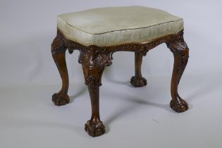 A Georgian style serpentine shaped walnut stool, with carved decoration, raised on cabriole