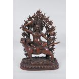 A Tibetan coppered bronze figure of a wrathful deity riding a mythical creature, double vajra mark