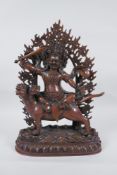 A Tibetan coppered bronze figure of a wrathful deity riding a mythical creature, double vajra mark