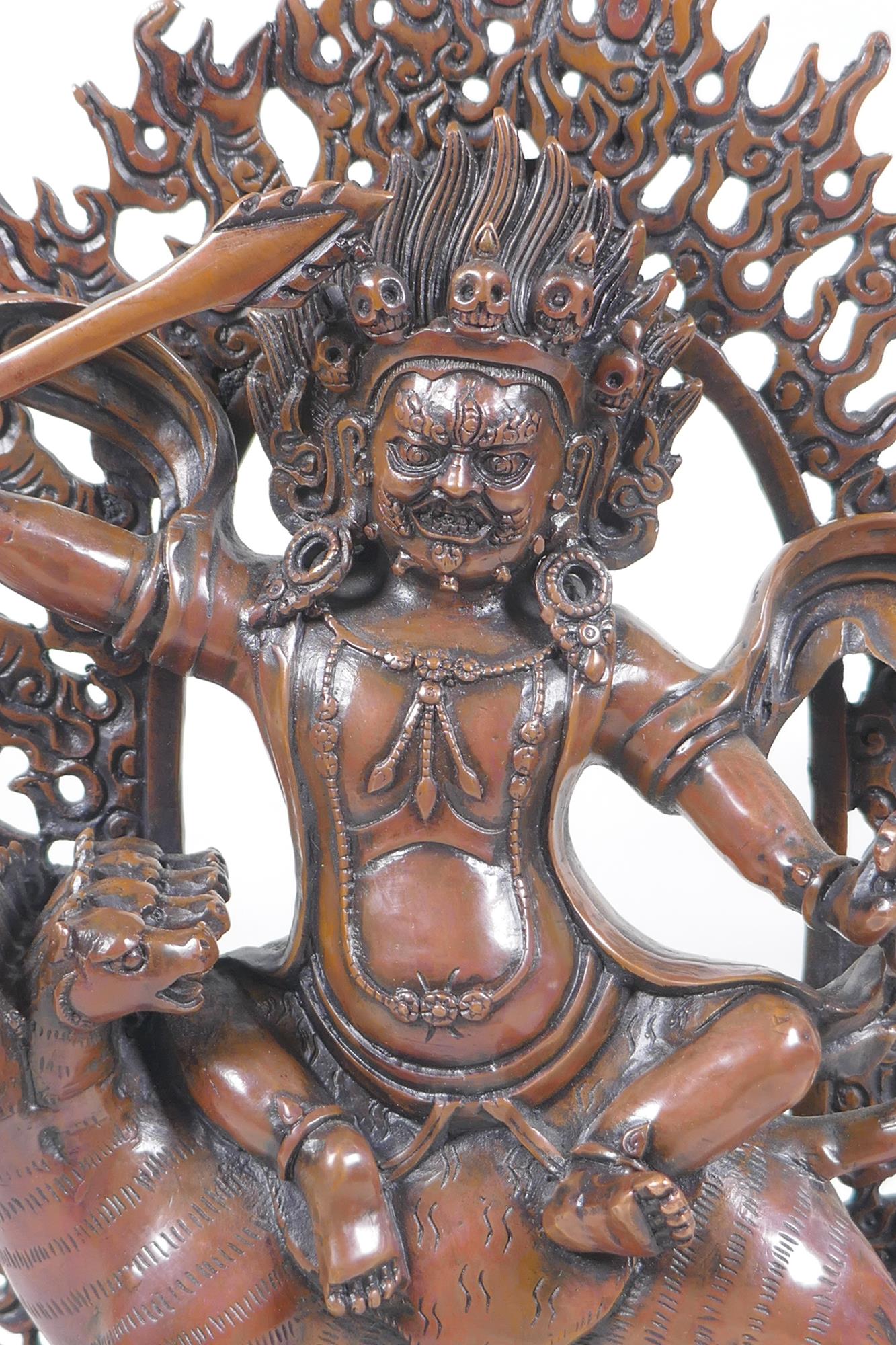 A Tibetan coppered bronze figure of a wrathful deity riding a mythical creature, double vajra mark - Image 2 of 6
